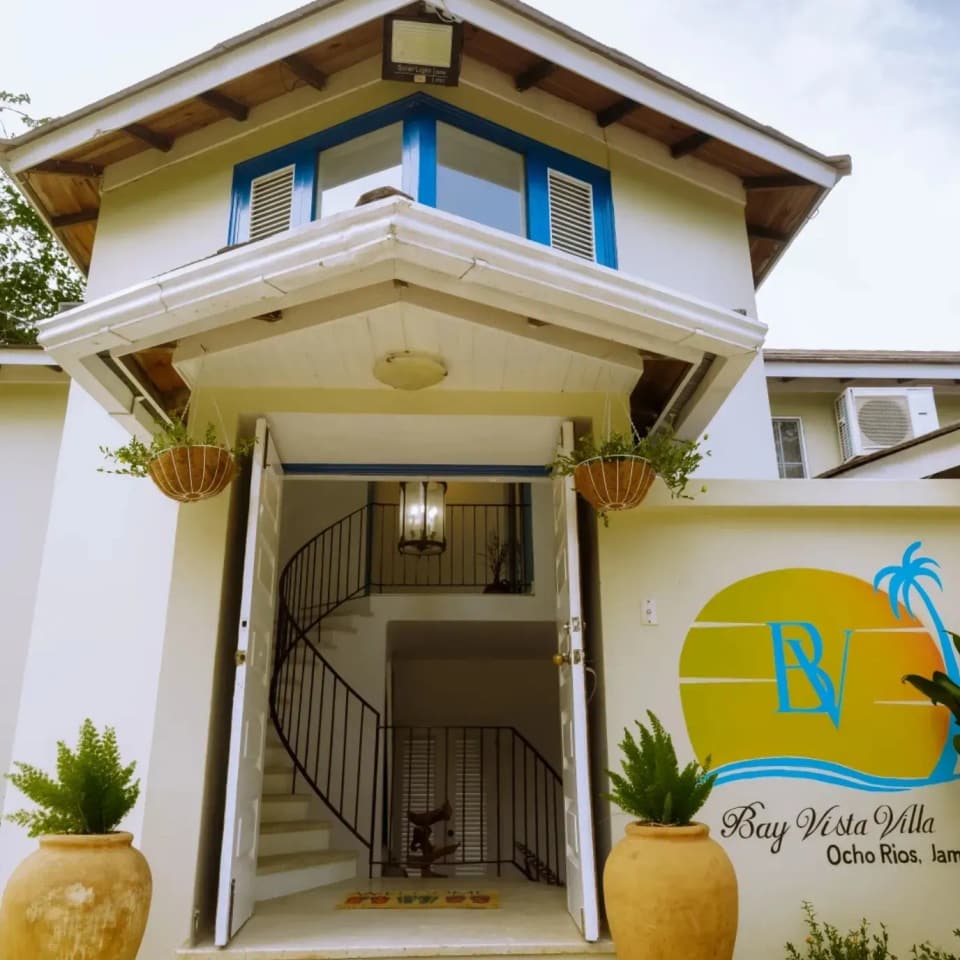 The front entrance of Bay Vista Villa with its sign and potted plants