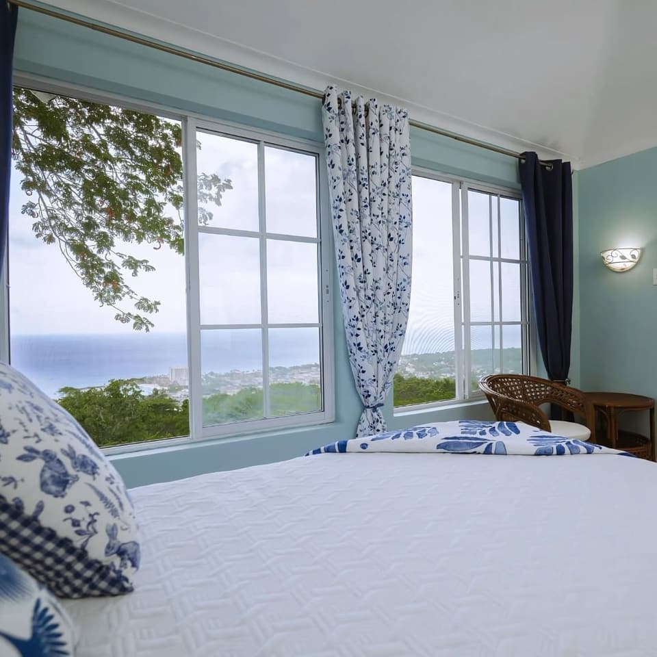 A bed by the window in Blue Serenity at Bay Vista Villa, looking to the sea