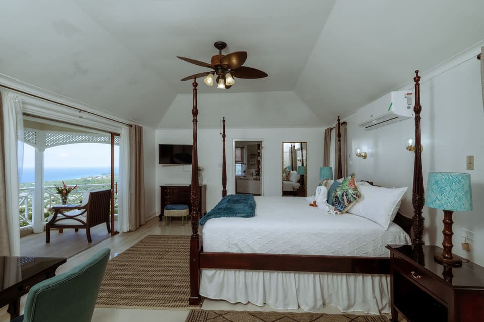 The primary suite at Bay Vista Villa with its four-poster bed and doors to the sea-view balcony