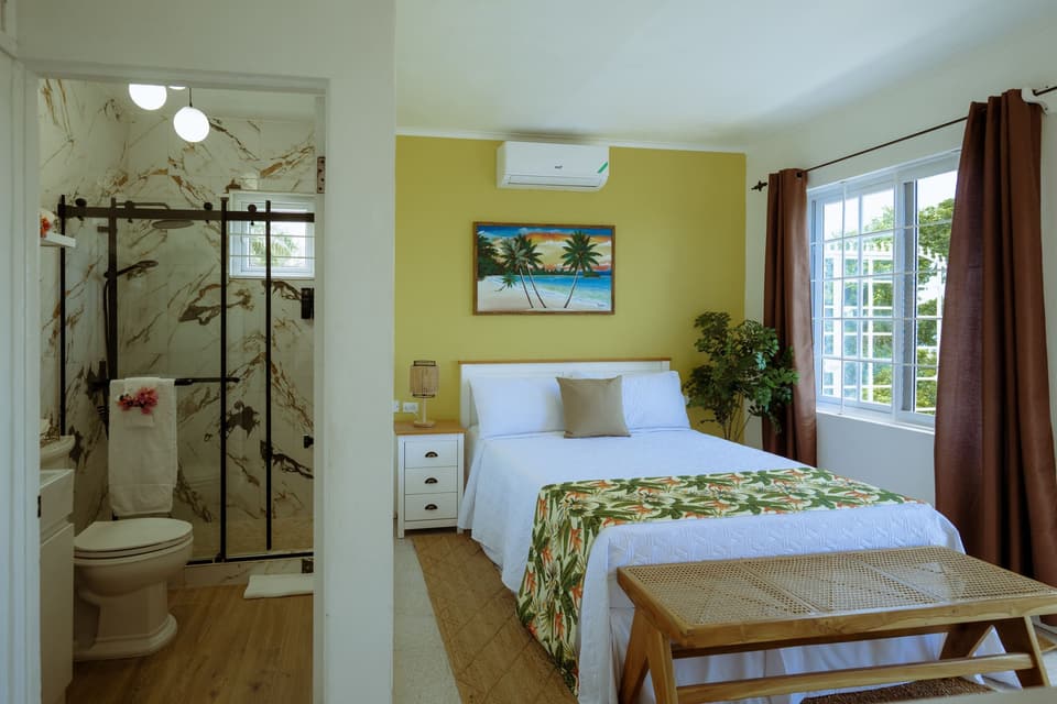 A queen bed with a tropical-print throw in the Yellow Bird Room at Bay Vista Villa