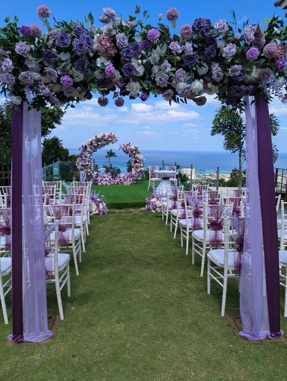 A lavender floral arch and white chairs on the lawn at Bay Vista Villa above the sea