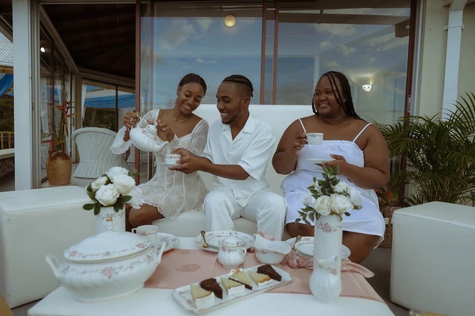 Three friends in white robes sharing afternoon tea on the terrace at Bay Vista Villa