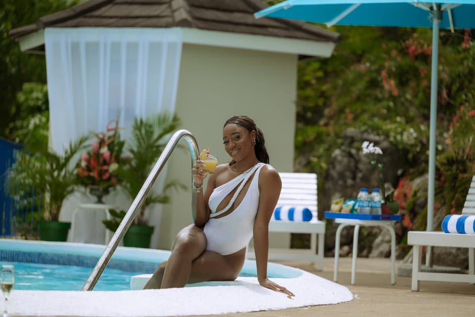 A guest sitting at the edge of the pool at Bay Vista Villa with a drink
