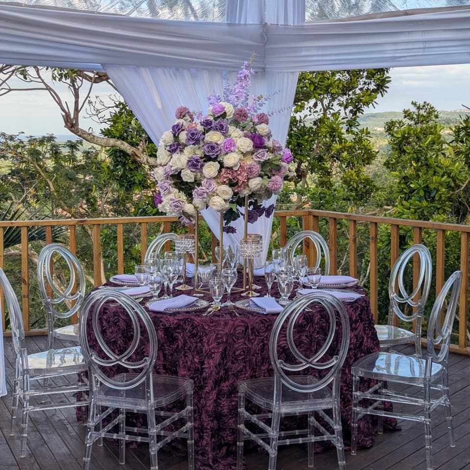 A reception table in plum and lilac on the deck at Bay Vista Villa with the sea beyond