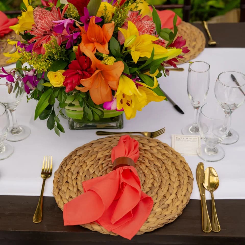 A tropical tablescape at Bay Vista Villa: heliconia, coral napkins and woven chargers